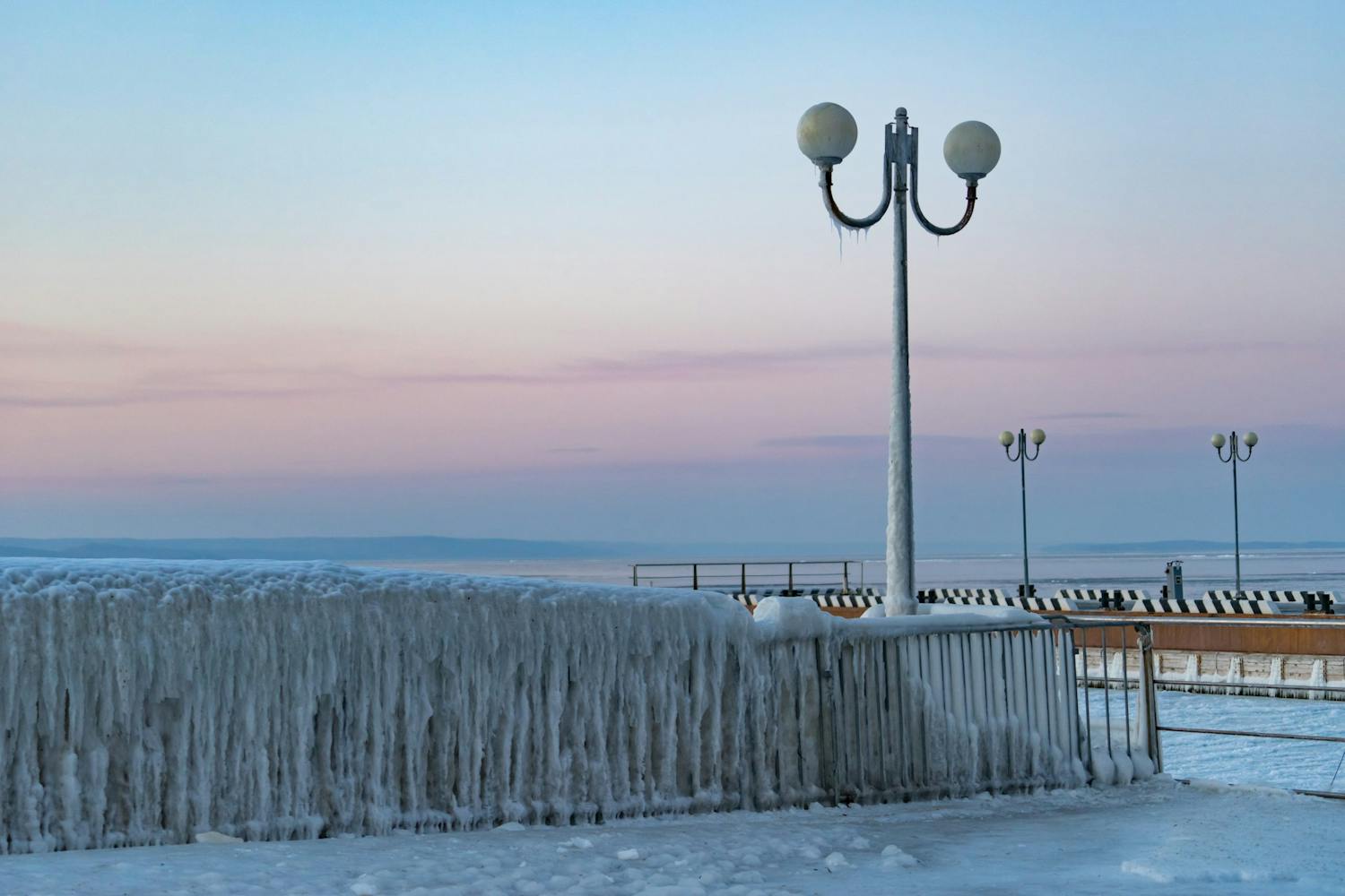 shutterstock 1271498233 t MYneMOosLGBSpaLUnS Jääpeitteistä aitaa ja valaisimia auringonlaskun valossa